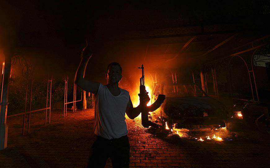 11 сентября 2012 года в результате нападения на посольство США в Бенгази был убит американский посол Кристофер Стивенс. Ответственность за атаку взяла на себя запрещенная террористическая группировка «Аль-Каида». Незадолго до нападения был выпущен фильм «Невинность мусульман», вызвавший массовые протесты мусульманского населения. Кроме того, лидер «Аль-Каиды» призывал к мести за убийство главы ячейки в Ливии&lt;br>На фото: вооруженный человек на фоне горящего посольства США в Бенгази