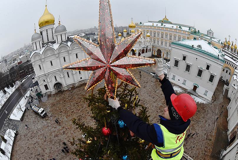 Москва, Россия. Рабочий устанавливает звезду на новогоднюю елку на Соборной площади Кремля