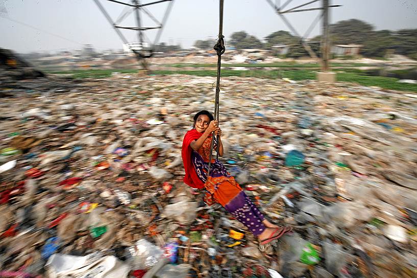 Дакка, Бангладеш. Девочка катается на качелях на мусорной свалке