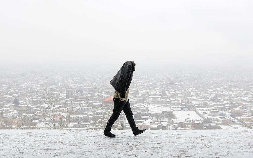 Кабул, Афганистан. Местный житель идет по заснеженному холму