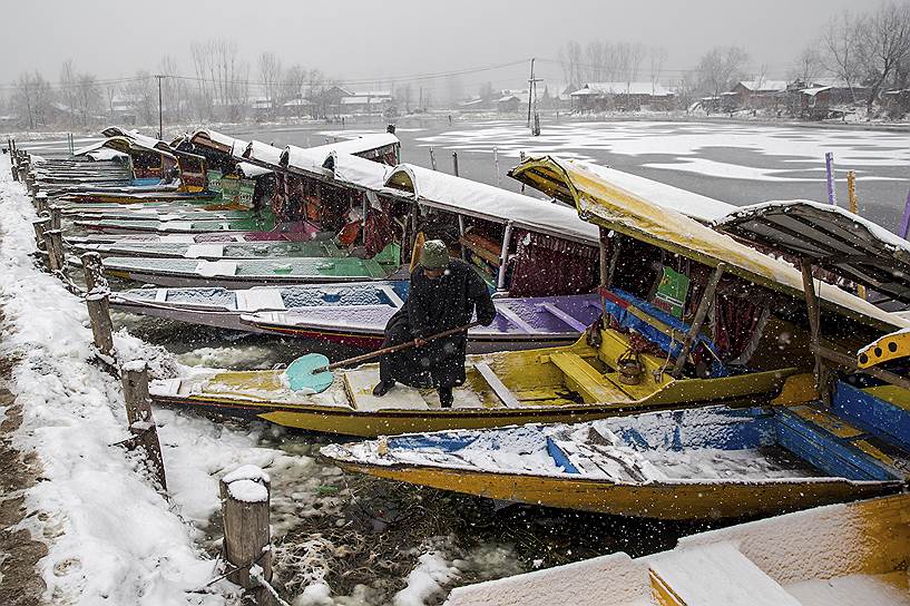 Срингар, Индия. Мужчина очищает свои лодки от снега