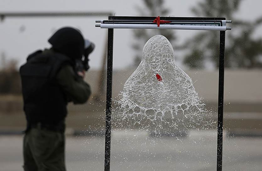 Иерихон, Палестина. Солдат стреляет по шару, наполненному водой, во время учений в молодежном лагере палестинских военных 