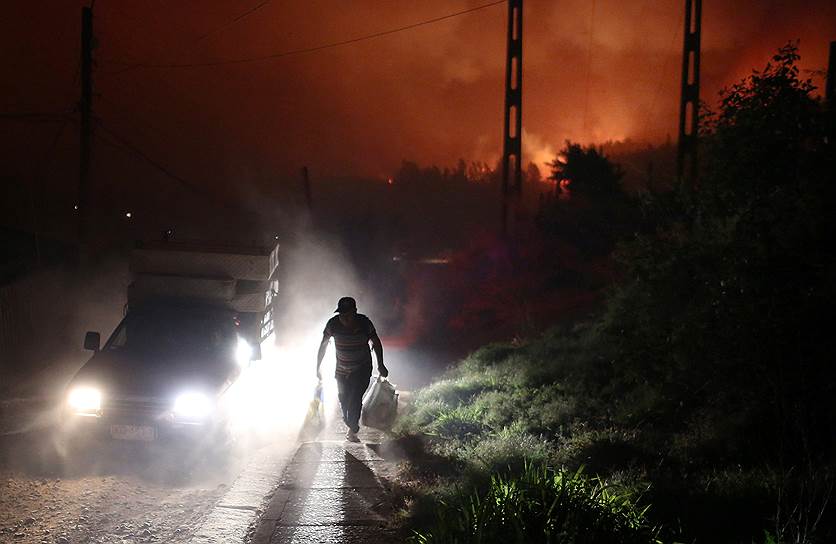 Санта Ольга , Чили.  Местный житель несет свои вещи после эвакуации из дома. Из-за лесных пожаров в нескольких регионах страны объявлено чрезвычайное положение, жертвами огня стали по меньшей мере шесть человек 
