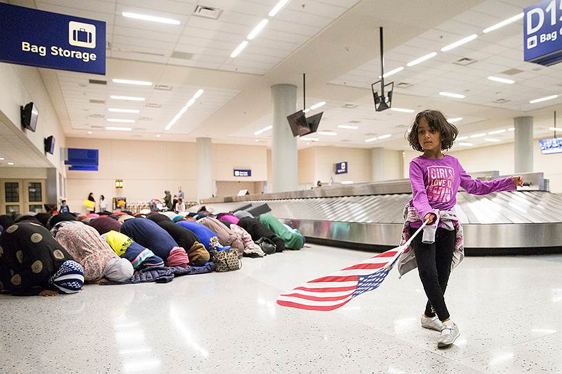 Даллас, США. Девочка танцует с американским флагом во время молитвы. В крупнейших аэропортах США прошли акции против указа Трампа о запрете въезда для мигрантов из мусульманских стран 