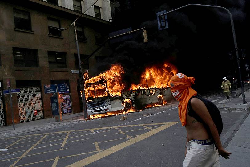 Рио-де-Жанейро, Бразилия. Местный житель на фоне горящего автобуса во время демонстрации против жесткой экономии бюджета