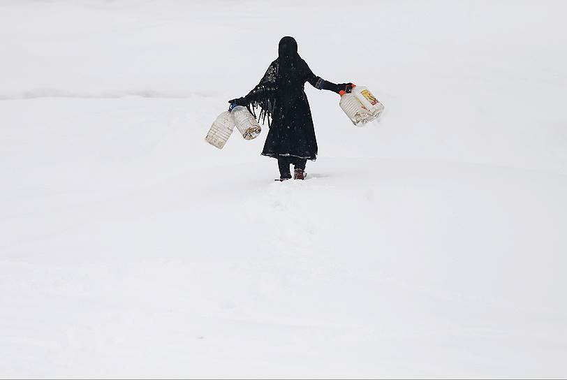 Кабул, Афганистан. Девочка с емкостями для воды идет по заснеженной равнине 
