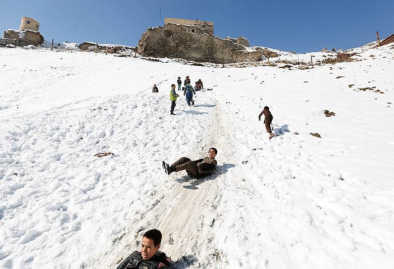 Кабул, Афганистан. Дети катятся с заснеженного холма 