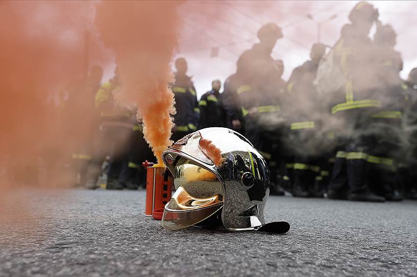 Афины, Греция. Шлем пожарного рядом с дымовой шашкой. Сотрудники пожарной службы провели акцию против нынешних условий труда