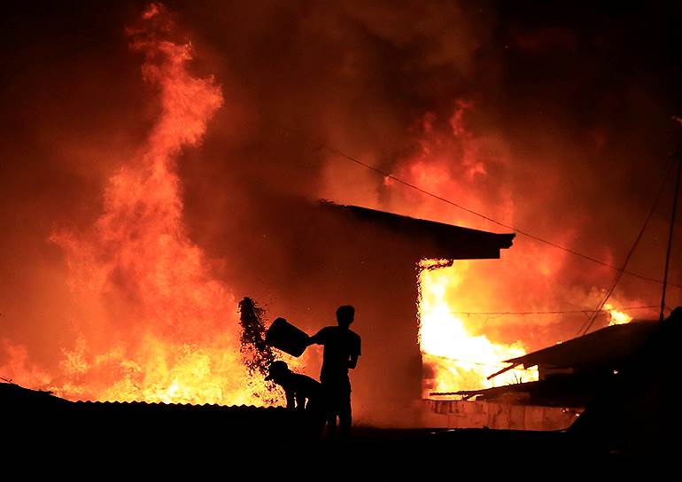 Манила, Филиппины. Местные жители пытаются потушить горящие дома. Из-за сильного пожара в одном из районов города около 15 тыс. человек лишились крова