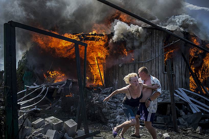 Победитель в номинации «События. Серия фотографий». Местные жители бегут от горящего дома, разрушенного во время бомбардировки деревни в Луганской области