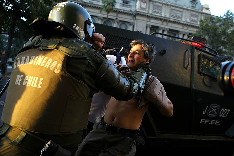 Сантьяго, Чили. Полицейский пытается задержать участника траурного митинга на годовщину смерти лидера профсоюзов Хуана Пабло Хименеса