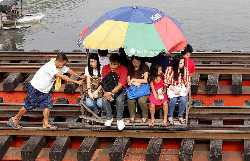 Манила, Филиппины. Жители пригорода едут на тележке по железнодорожным путям