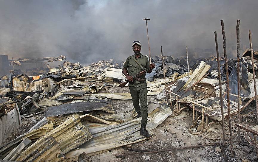 Могадишо, Сомали. Полицейский идет по обломкам центрального рынка столицы, который сгорел накануне