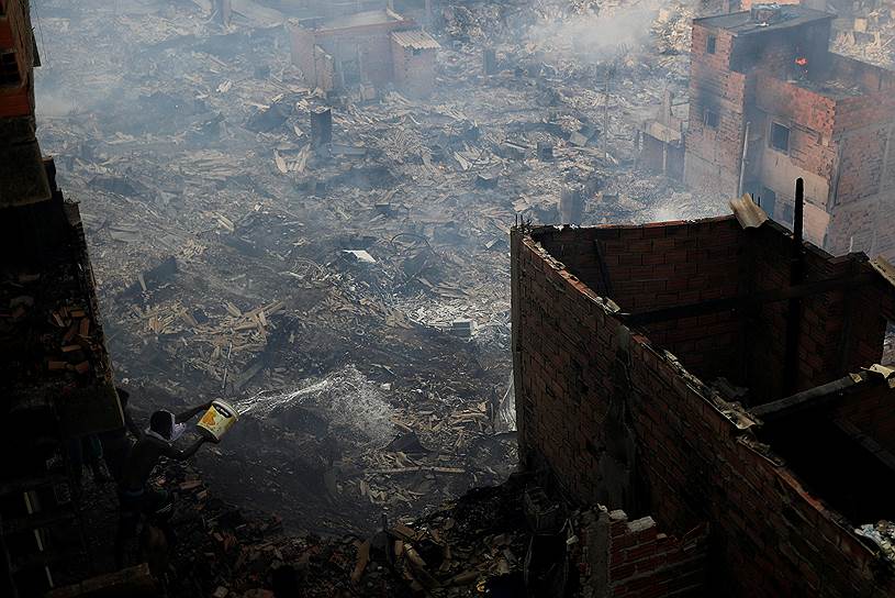 Сан-Паулу, Бразилия. Местные жители выливают воду из окна, чтобы потушить пожар в трущобах  