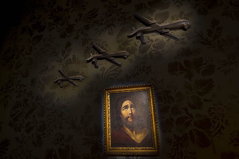 Стена, украшенная картиной с изображением Иисуса Христа с летящими над ней военными самолетами