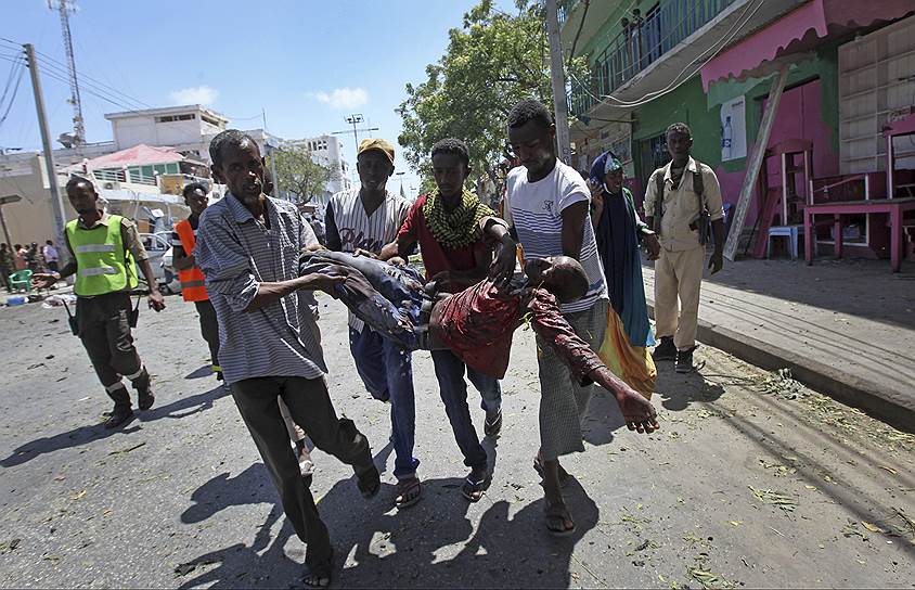 Могадишо, Сомали. Спасатели несут раненного во время взрыва человека. По меньшей мере два человека погибли после того, как террористы взорвали машину на оживленной улице 