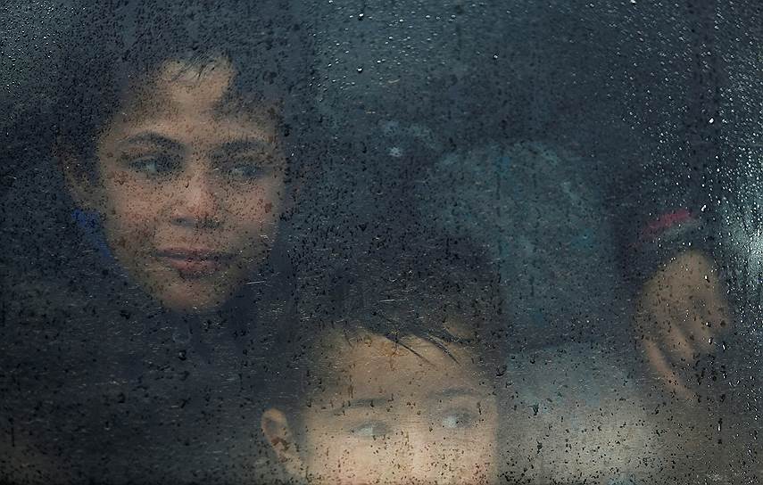 Мосул, Ирак. Дети смотрят на дождь из окна автобуса по дороге в специальный лагерь для беженцев