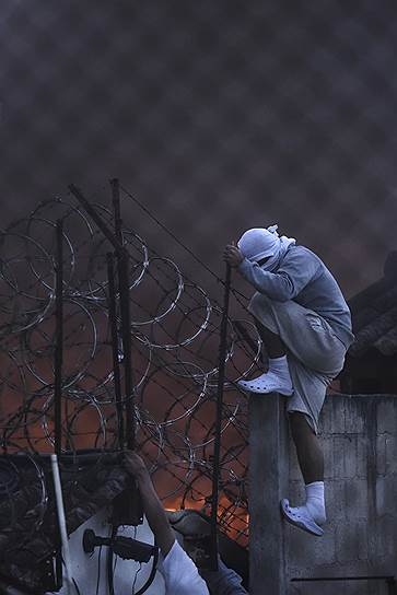 Сан-Хосе-Пинула, Гватемала. Житель приюта для подростков перелезает через забор во время бунта в учреждении 8 марта. Тогда погибли 19 подростков, еще 25 получили ожоги разной степени