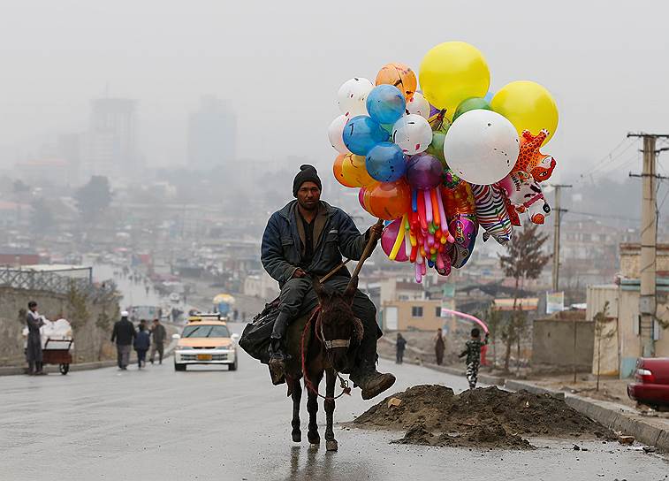 Кабул, Афганистан. Торговец воздушными шарами едет на осле во время празднования наступления весны
