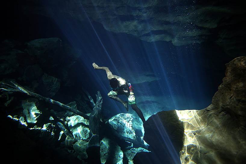 Штат Баия, Бразилия. Работник ныряет в озеро в пещере Poco Azul, чтобы достать вещи, которые уронили туристы