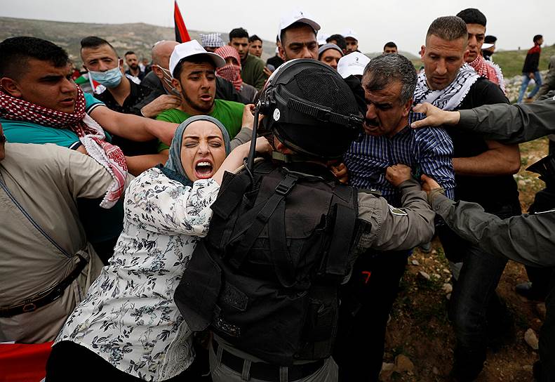 Мадама, Палестина. Палестницы пытаются не позволить израильским военным задерживать протестующих во время марша