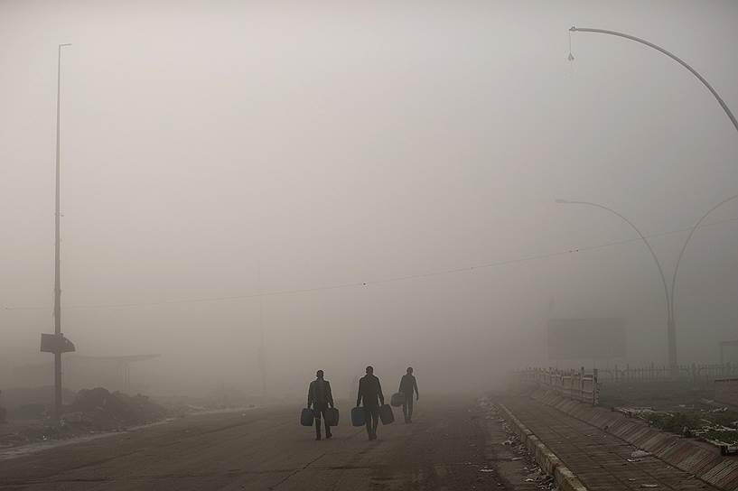 Мосул, Ирак. Местные жители идут по туманной дороге в районе города, освобожденном от террористов «Исламского государства» (запрещено в РФ)