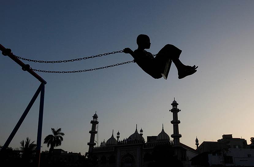 Карачи, Пакистан. Местный мальчик катается на качелях на закате