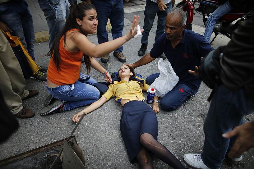 Каракас, Венесуэла. Демонстранты помогают единомышленнице, пострадавшей от слезоточивого газа, примененного полицией во время антиправительственных акций