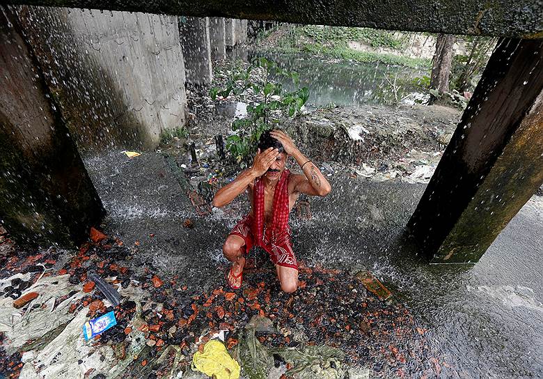 Калькутта, Индия. Мужчина умывается водой, текущей из неисправных труб