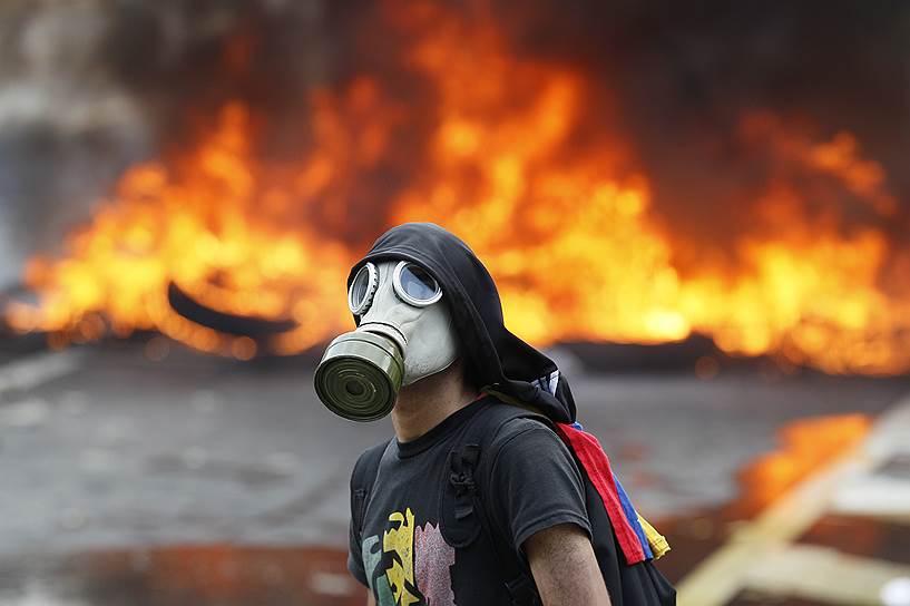 Венесуэла, Каракас. Участник протестов на фоне горящих баррикад 