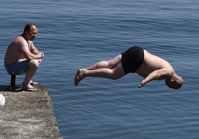 Алушта, Россия. Мужчина прыгает с пирса в море