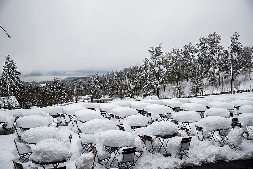 Осло, Норвегия. Столы и стулья летнего кафе под снегом