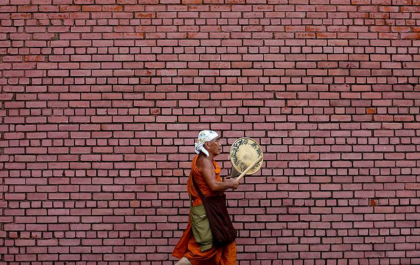 Коломбо, Шри-Ланка. Монах играет на традиционном музыкальном инструменте во время утренней прогулки по городу
