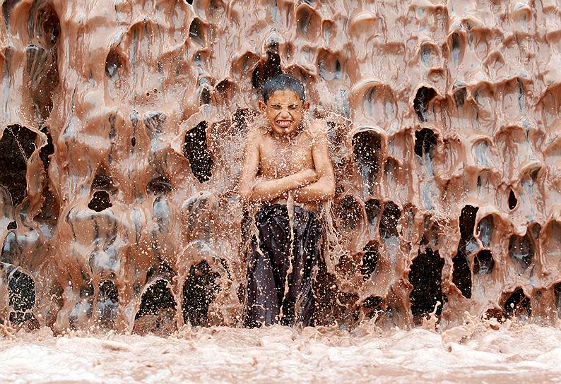 Джалалабад, Афганистан. Мальчик охлаждается в грязном водопаде