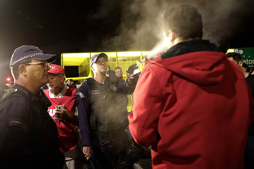 Бразилиа, Бразилия. Полицейский распыляет перцовый аэрозоль перед участником демонстрации против президента страны Мишела Темера