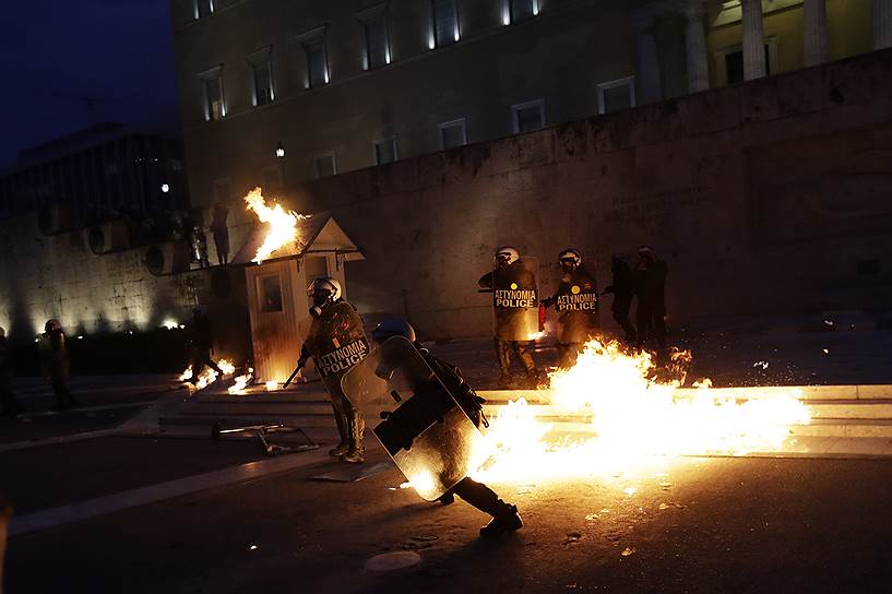 Афины, Греция. Полицейские бросают коктейли Молотова в демонстранта. В столице страны прошли акции против новой волны мер жесткой экономии