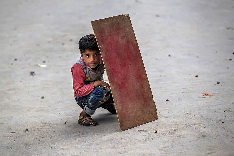 Сринагар, Индийский Кашмир. Кашмирский мальчик держит самодельный щит из фанеры,  чтобы защититься от камней во время столкновений протестующих с полицией 