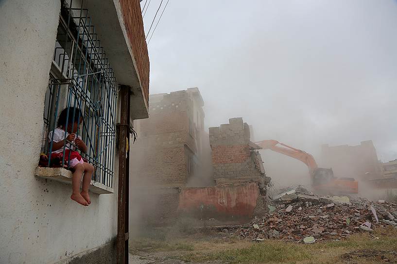 Диярбакыр, Турция. Сидящий на окне ребенок наблюдает, как экскаватор сносит здание в рамках плана по трансформации города