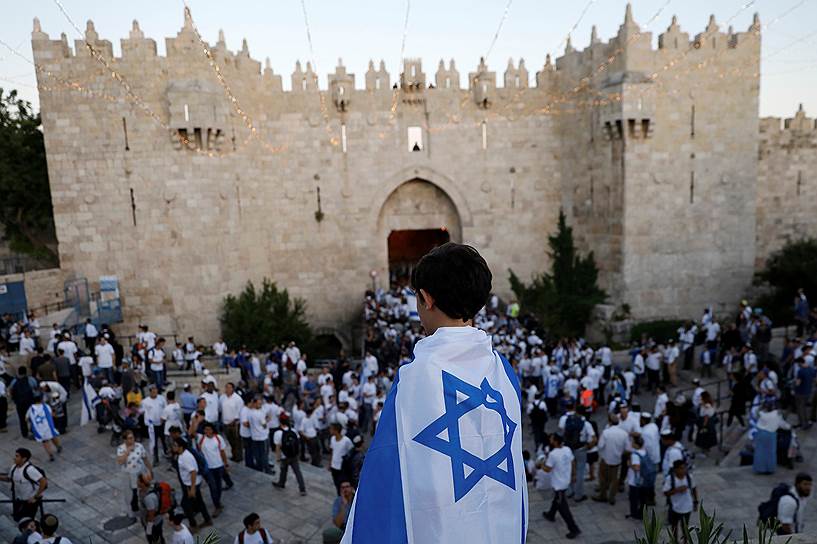 Иерусалим, Израиль. Завернутый во флаг Израиля мальчик наблюдает за парадом, посвященным Дню объединения Иерусалима