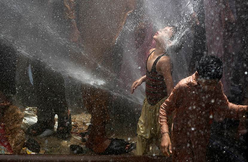Карачи, Пакистан. Мальчик под струями холодной воды. В качестве протеста против отключения коммуникаций местные жители продырявили трубы с водой 