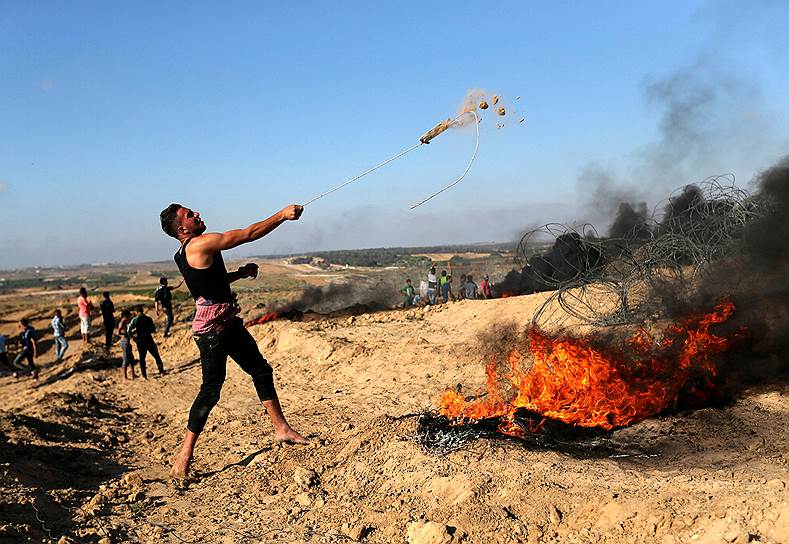 Сектор Газа. Палестинец бросает камни в израильских военных во время столкновений на границе 