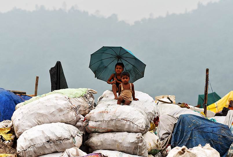 Гувахати, Индия. Дети сидят на мешках мусора, отправляемого на переработку