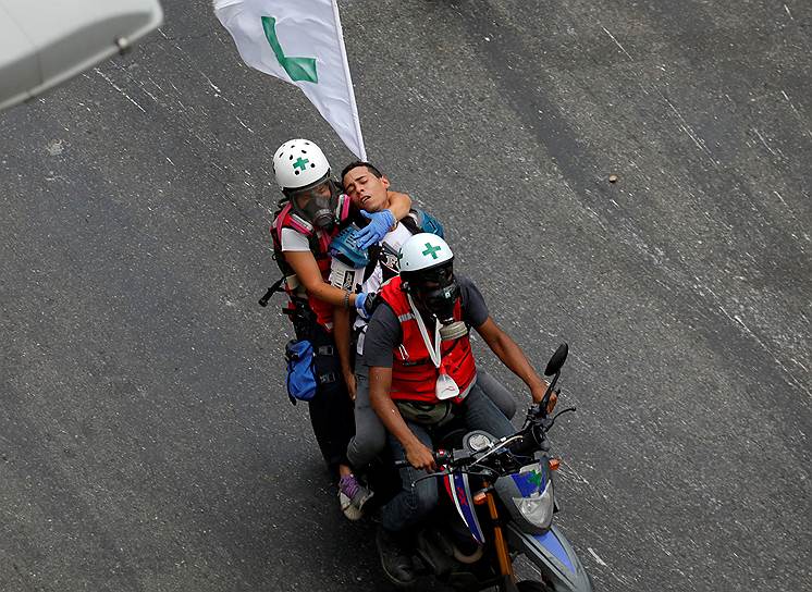Каракас, Венесуэла. Волонтеры помогают раненному во время антиправительственных протестов демонстранту