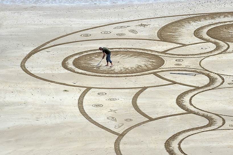 Тенби, Великобритания. Художник Марк Тринор создает картину на песчаном пляже