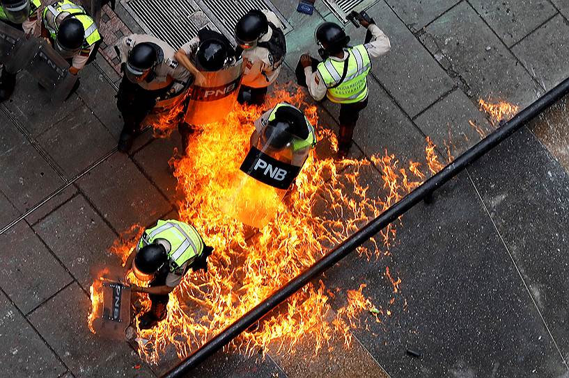 Каракас, Венесуэла. Полицейские тушат пожар, устроенный демонстрантами во время антиправительственной акции 