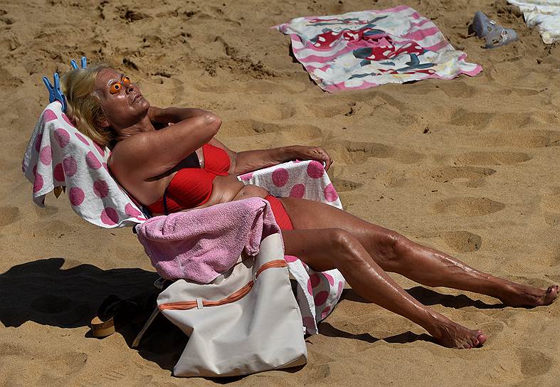 Хихон, Испания. Женщина принимает солнечную ванну 