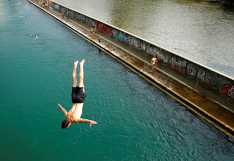 Цюрих, Швейцария. Местный житель прыгает с моста в реку Лиммат в жаркий день  