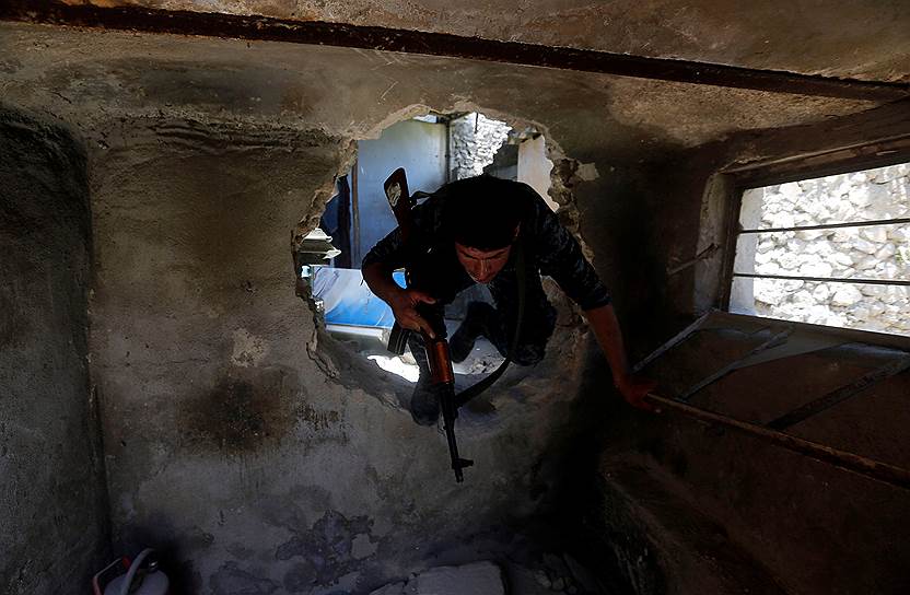 Мосул, Ирак. Солдат правительственной армии пролазит через в дыру в стене