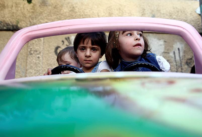 Дума, Сирия. Дети в игрушечном автомобиле во время празднования окончания священного месяца рамадан