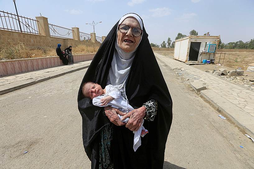 Мосул, Ирак. Женщина с ребенком на руках выходит из осажденного боевиками квартала